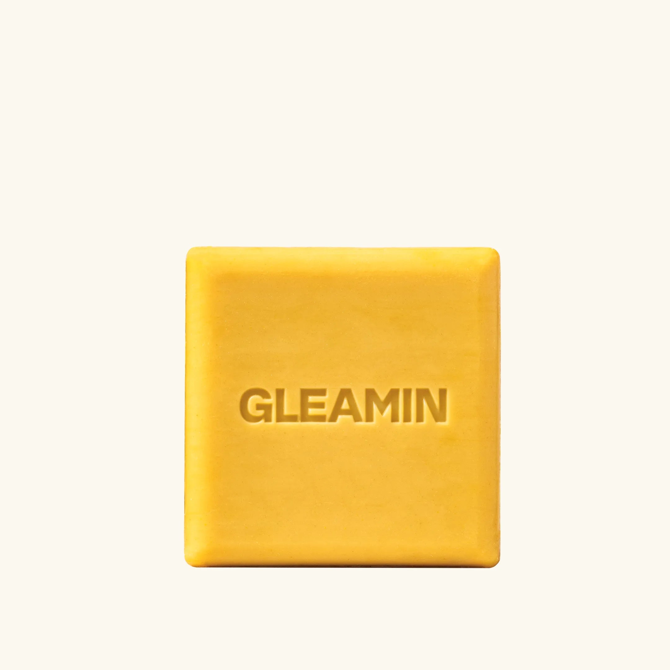 Brightening bar soap in a golden square shape with GLEAMIN embossed, designed to cleanse and enhance skin radiance