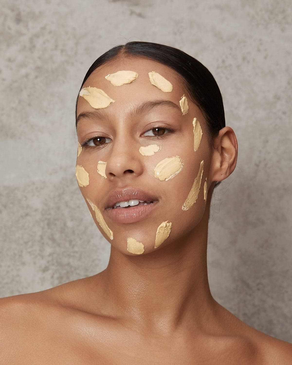 Model with dabs of yellow clay mask across her face