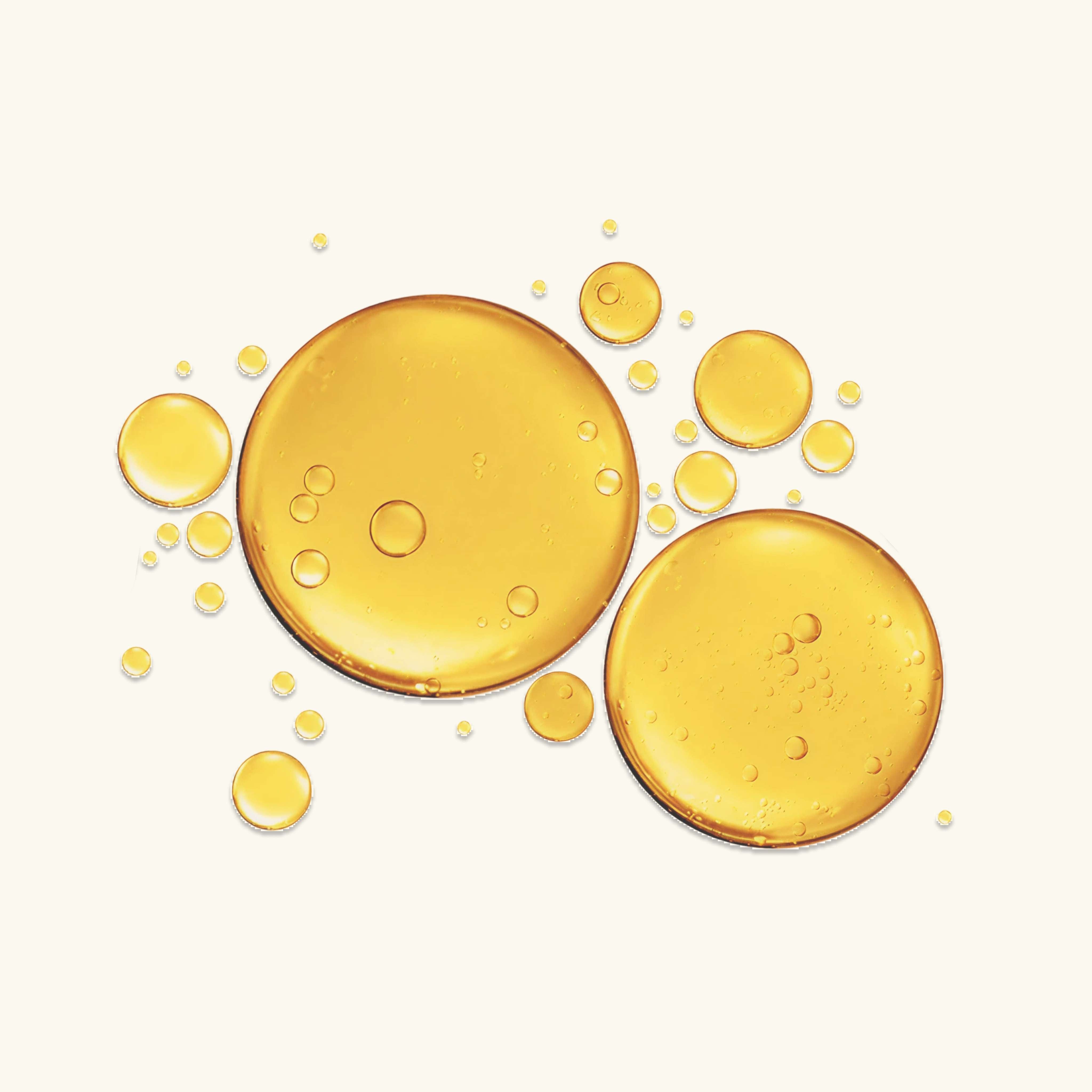 Oil swatch with golden droplets in various sizes, showing a lightweight, nourishing texture for glowing skin