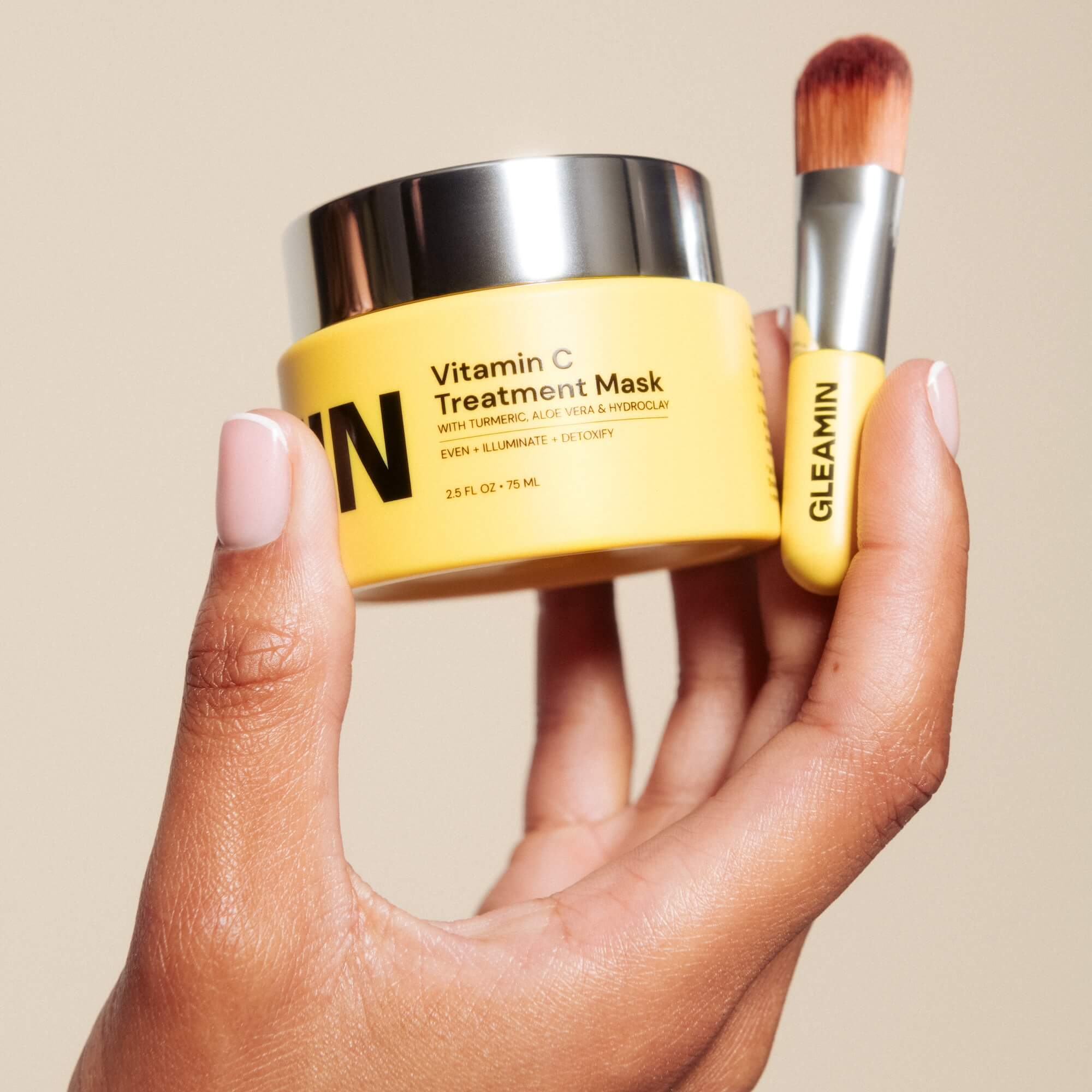 a hand holding a yellow container with a brush
